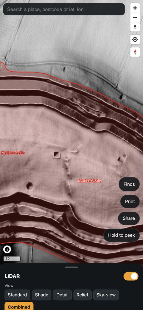 The app showing Maiden Castle's ramparts in the Pro Combined view, with the Scheduled Monument tinted red.